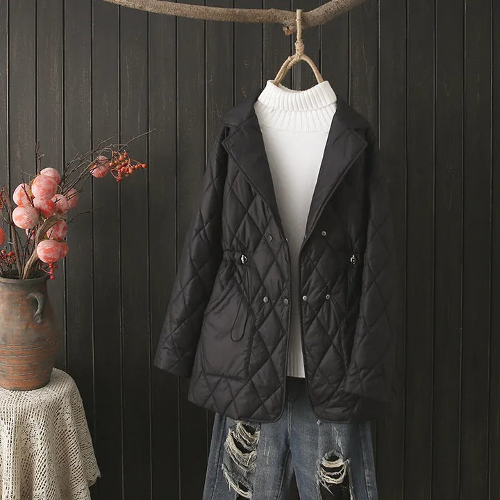 Schwarze gesteppte Damenjacke, elegant, Herbstmode, vor Holzwand drapiert.
