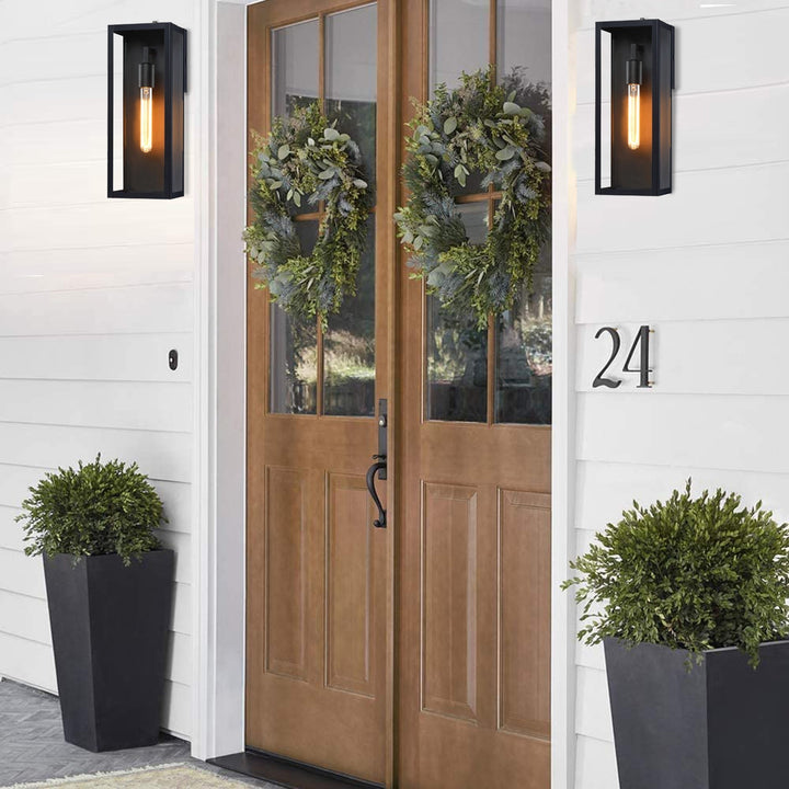Two black outdoor wall lanterns with clear glass flank a double wooden front door.