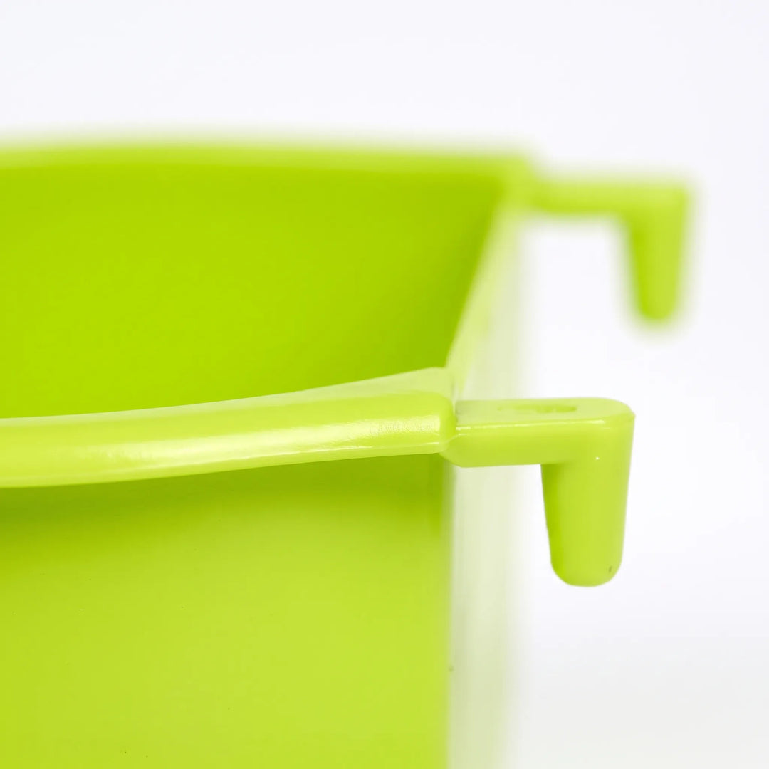 Close-up of the bowl's rim and hook tab in green plastic, showing the molded detail of the part that grips the cage bars. 3