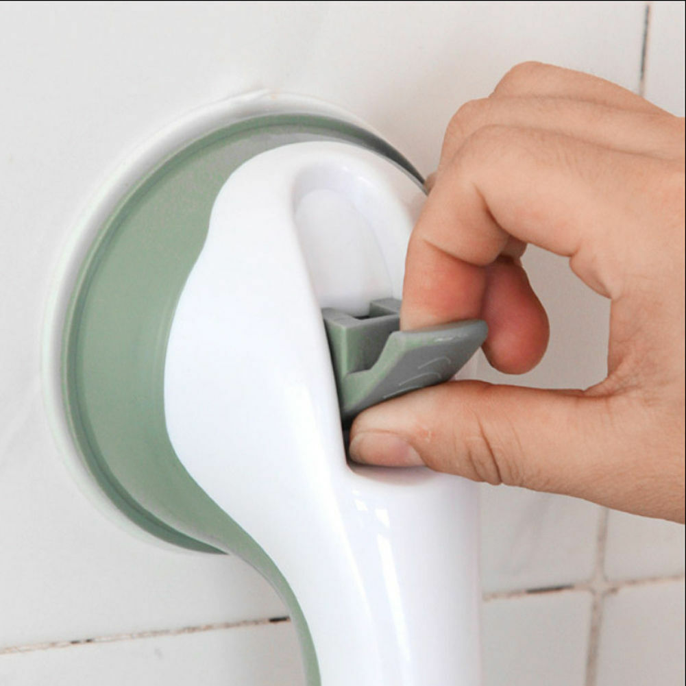Fingers lift the gray release tab on a grab bar attached to white bathroom tiles.