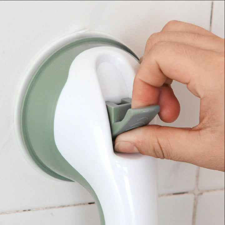 Fingers lift the gray release tab on a grab bar attached to white bathroom tiles.