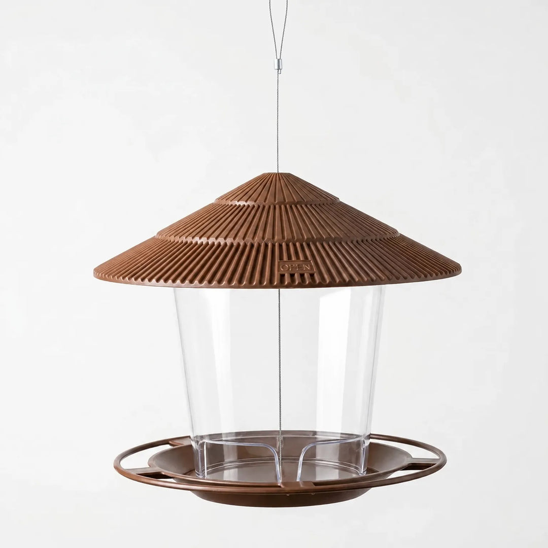 Empty brown feeder against a plain background, showing the ribbed roof, clear tube and round perch tray on its hanging wire. 4