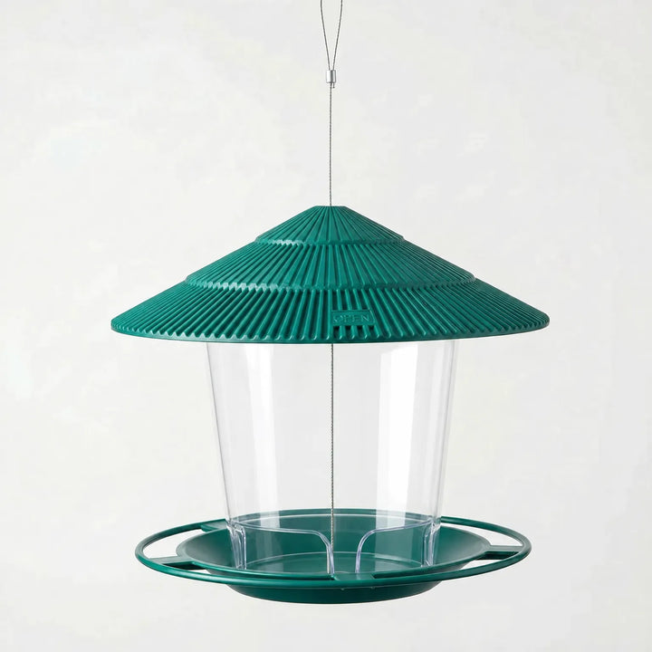 Empty dark green feeder with ribbed tiered roof, clear tube and circular tray, hanging from a thin wire loop. 6