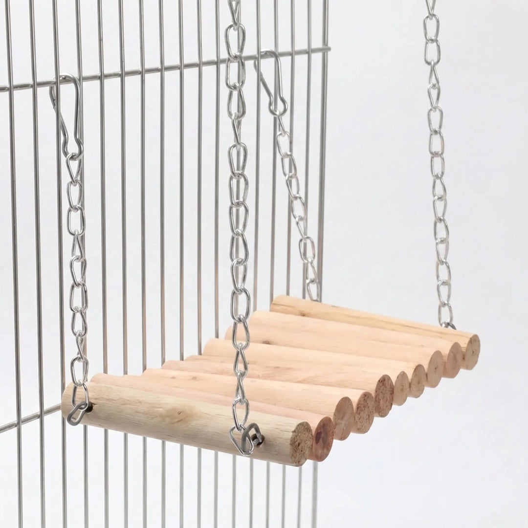 Wooden log swing hanging by metal chains and snap hooks from the bars of a wire cage, seen from a low angle. 1