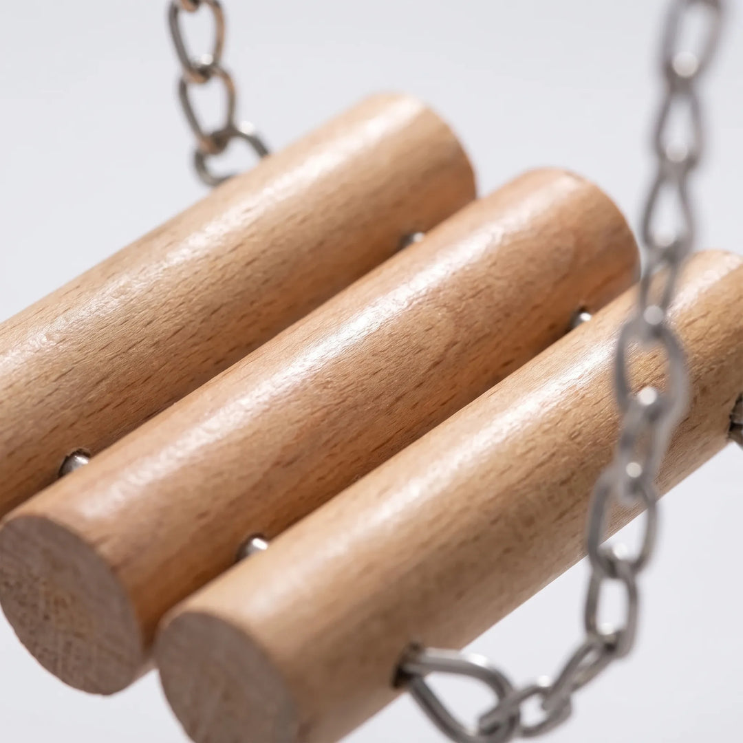 Close-up of three smooth wooden logs on the swing, joined with small metal pins and attached to metal chains. 3