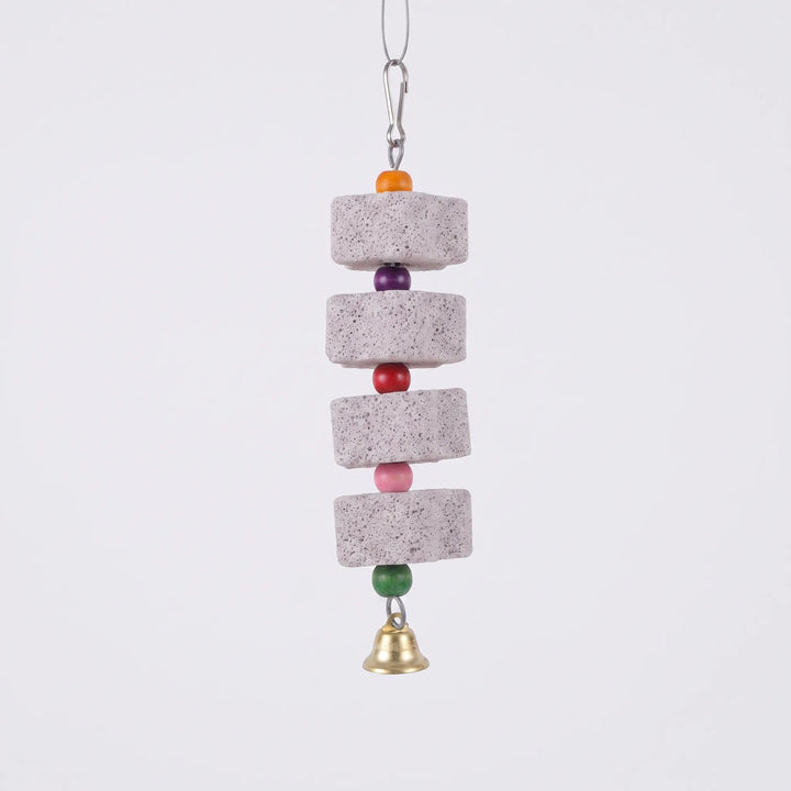Hanging toy on a plain white background: four porous gray stone blocks separated by colorful wooden beads, with a brass bell at the bottom. 1