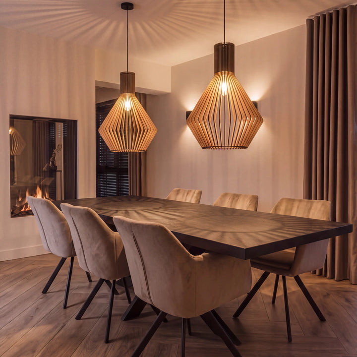 Two slatted wooden pendant lamps with angular diamond-shaped shades above a dark dining table with beige chairs
