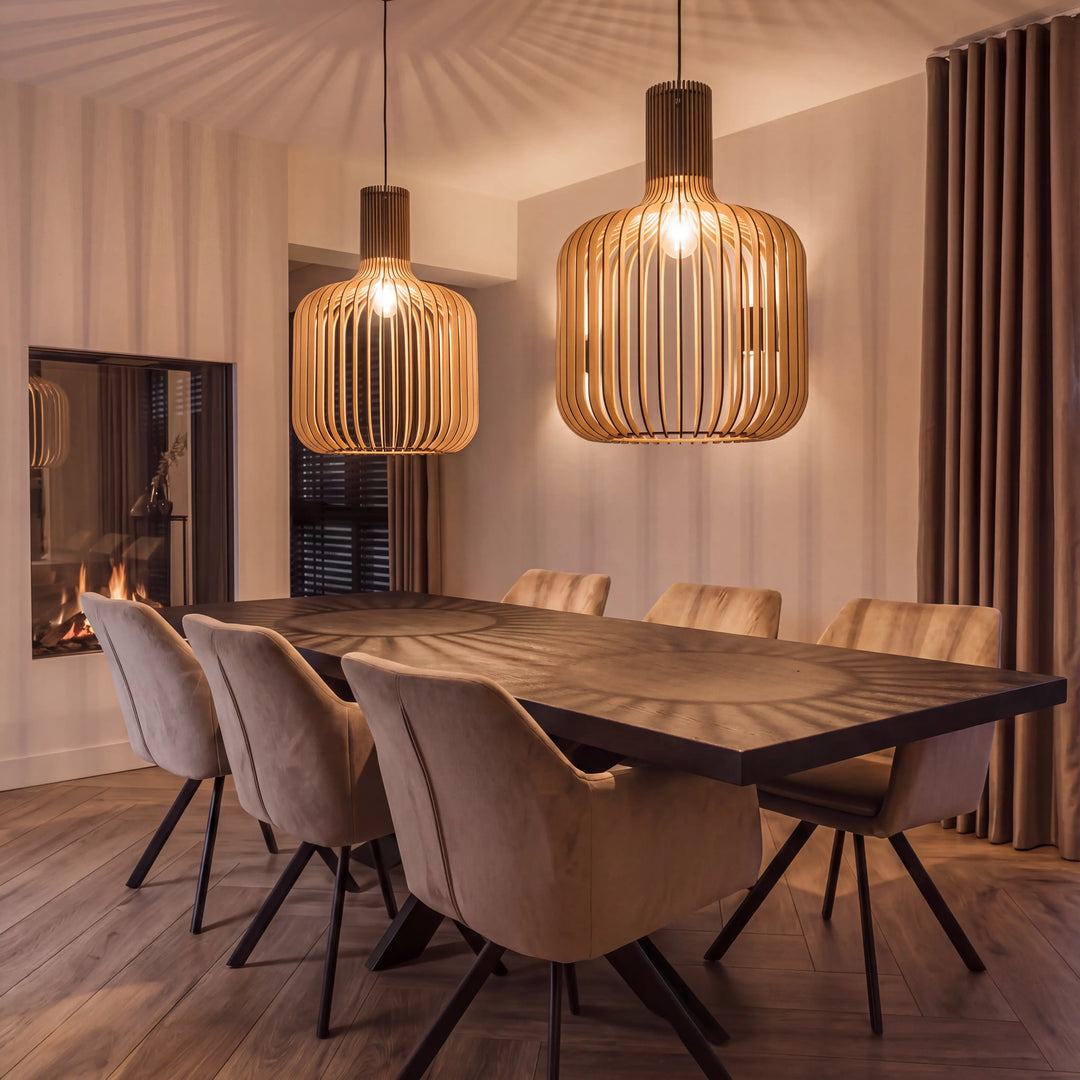 Two slatted wooden pendant lamps with rounded bottle-shaped shades above a dining table beside a fireplace