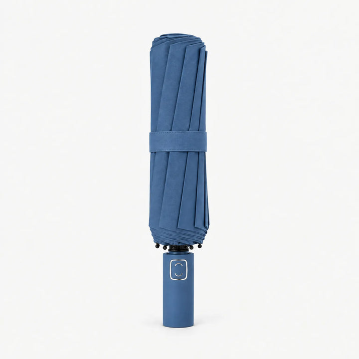 Folded denim blue umbrella with matching strap standing upright on its handle against a white background. 11