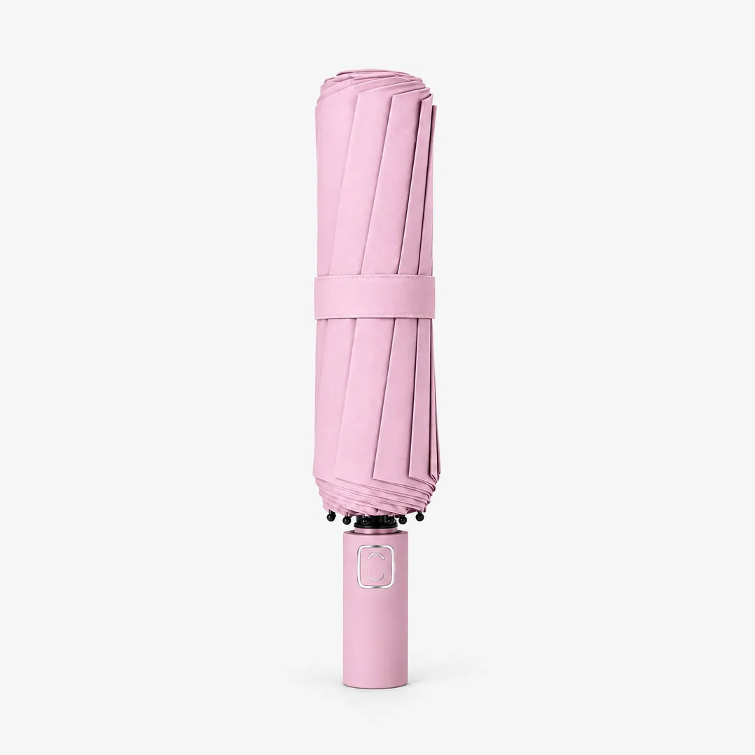 Folded pink umbrella with matching fabric strap standing upright on its handle against a white background. 7