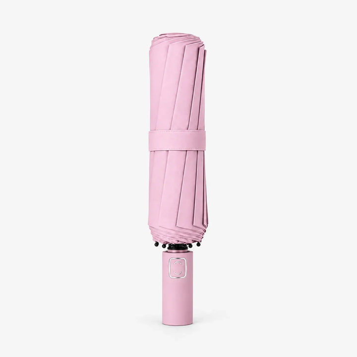 Folded pink umbrella with matching fabric strap standing upright on its handle against a white background. 7