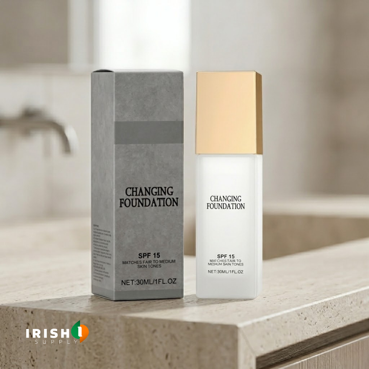 Frosted white square bottle with gold cap standing beside its gray carton on a stone bathroom counter.