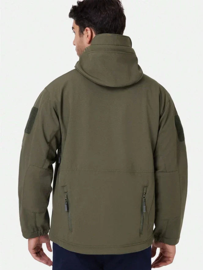 Back view of the olive green jacket on a model, showing hood, sleeve patches and lower zip pockets 6