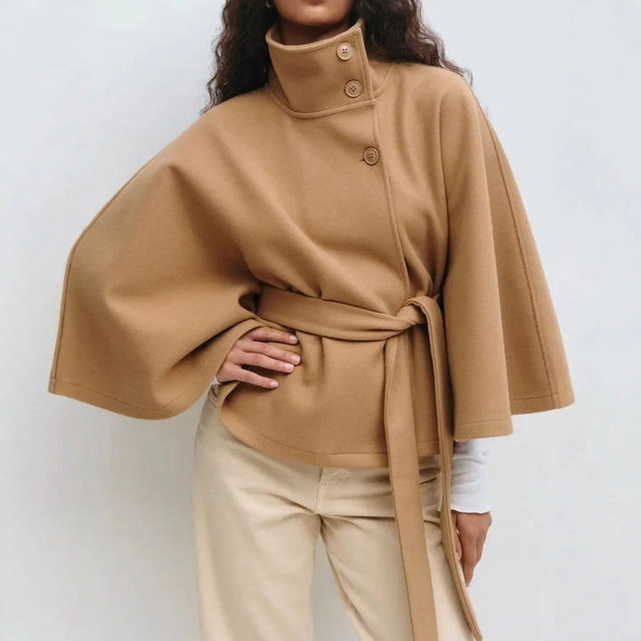 Close-up of the camel cape jacket on a model, showing the high collar buttons and wide sleeves 8