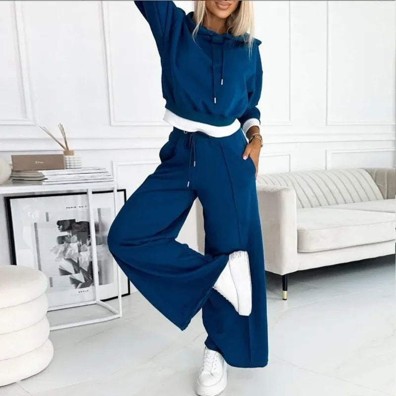 Woman in a deep blue hoodie set with white hem and cuffs, one leg raised 8