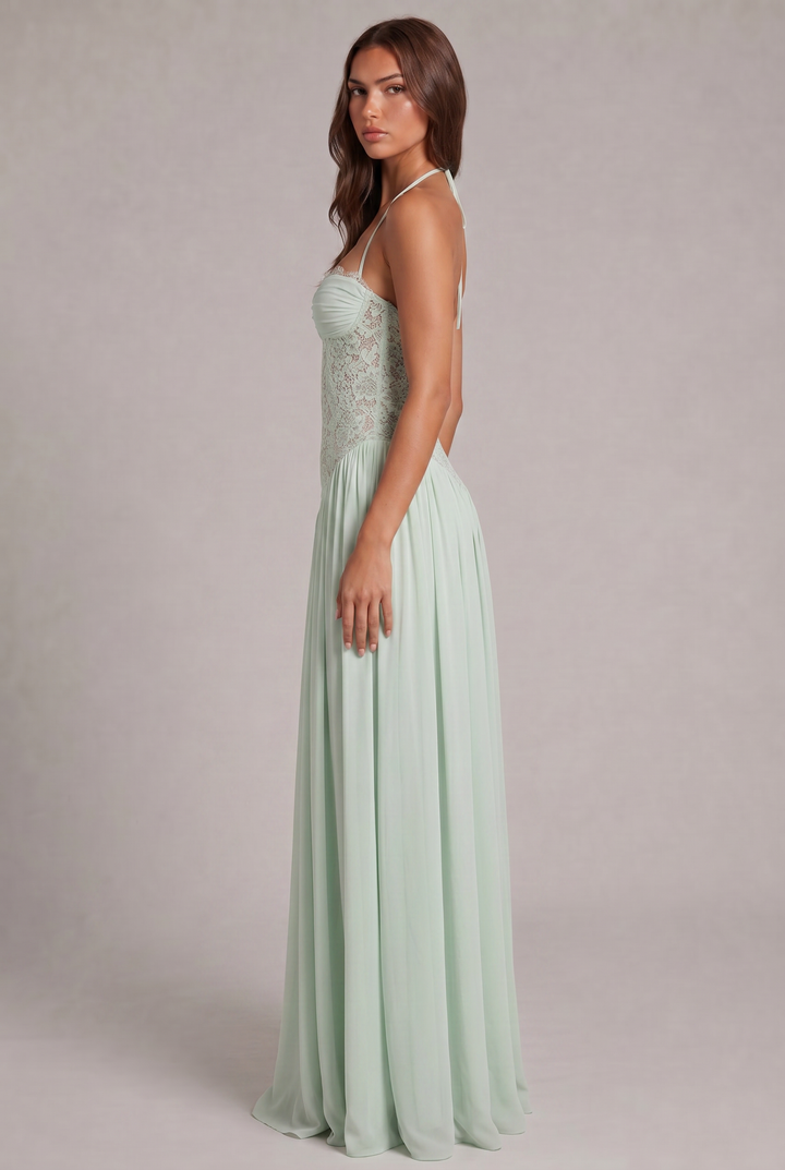 Side view detail of the green dress on a model, with straps at the neck and a long skirt.