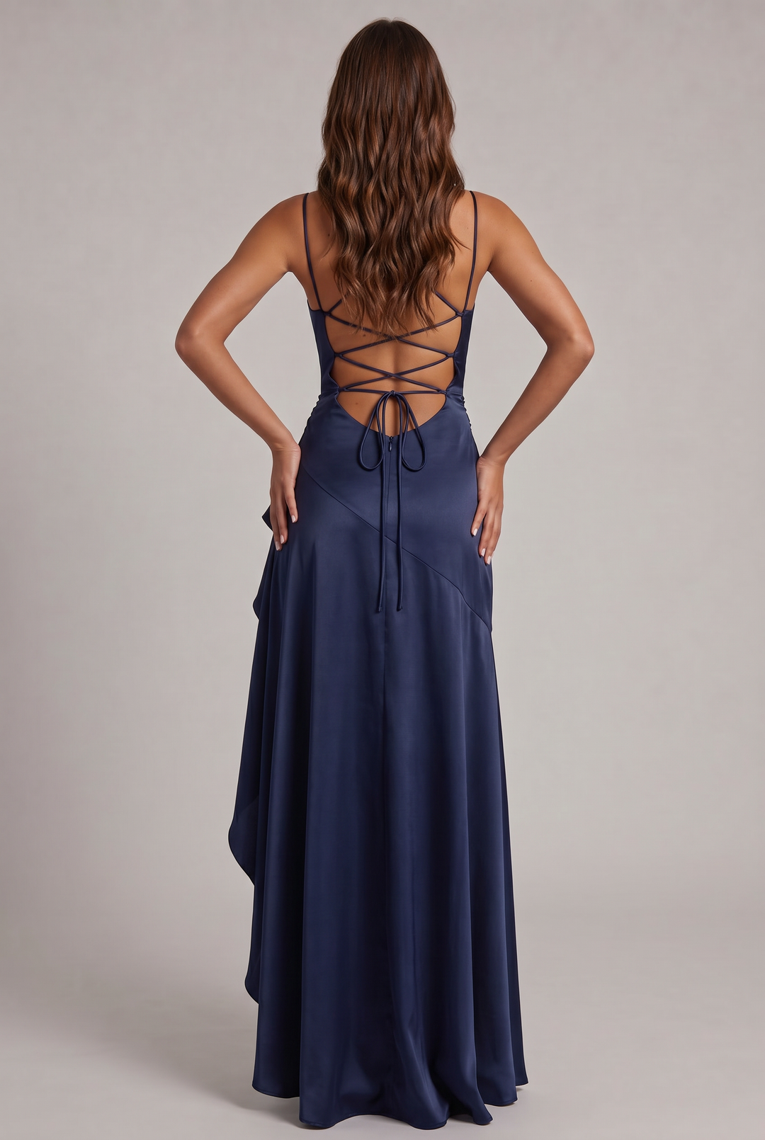Back view of the navy satin dress showing crisscross lacing, tie closure and zipper, hands on hips 8