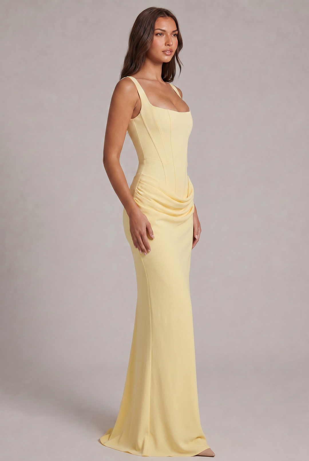 Side view of the pale yellow gown on a model, showing the corset seams, draped hip detail and slim skirt with a small train. 23