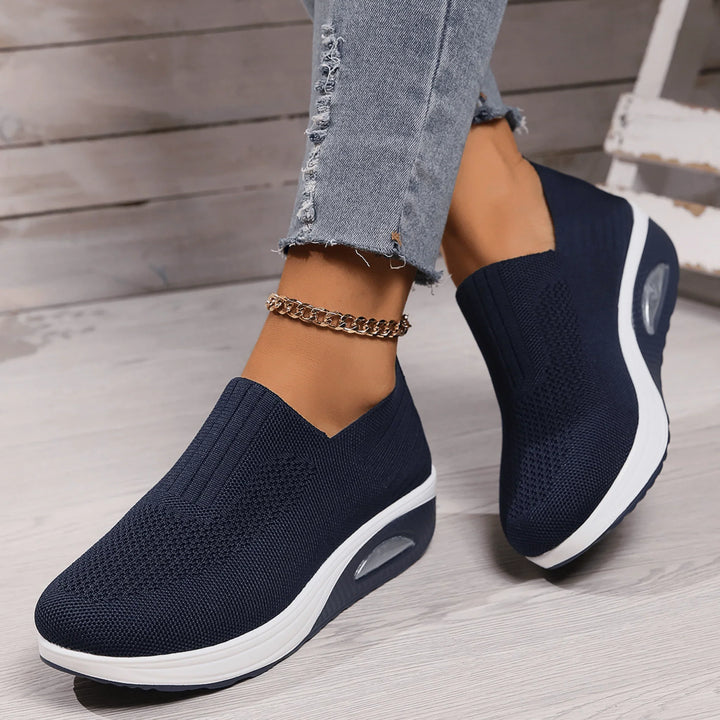 Navy blue knit slip-on sneakers with white soles and visible air cushion detail