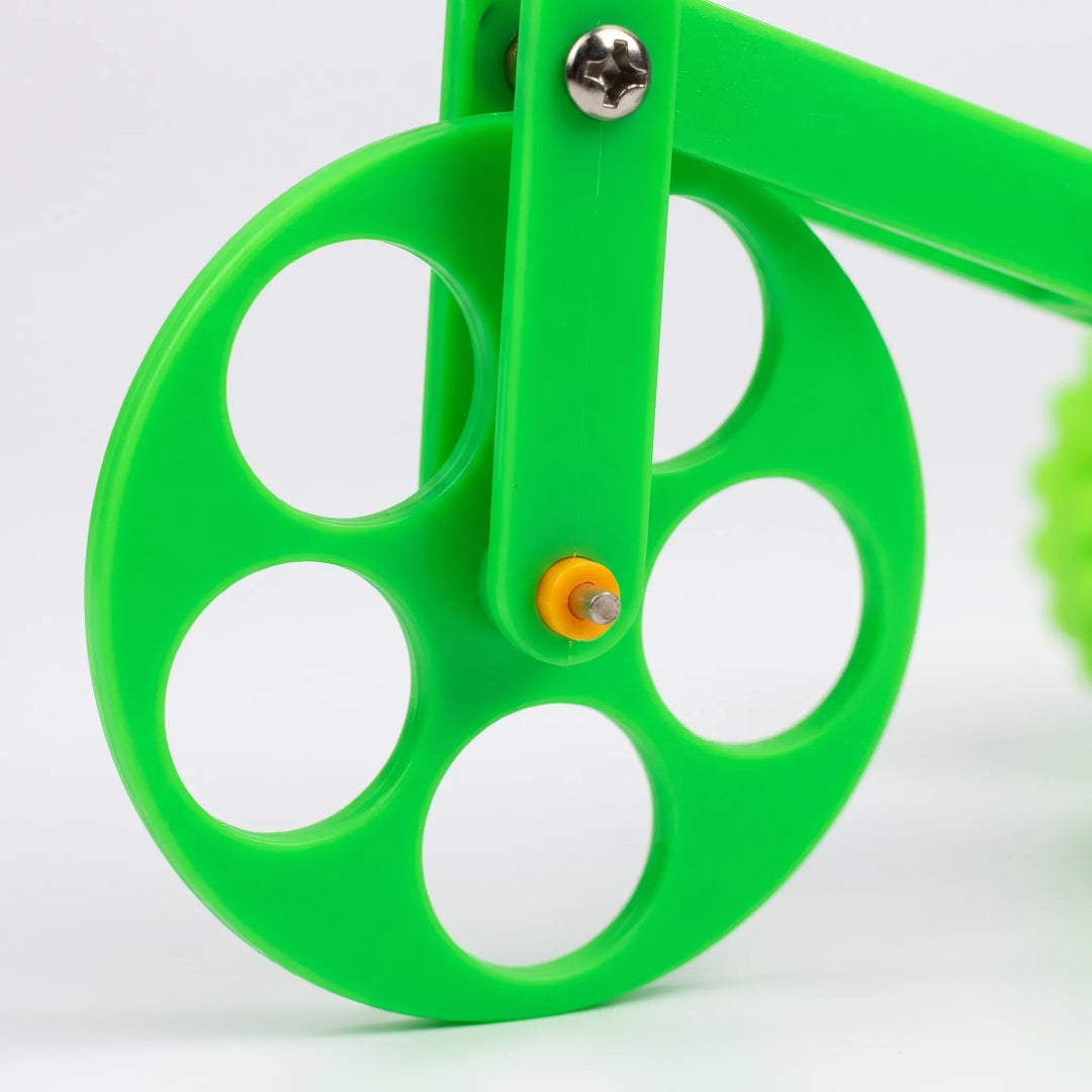 Close-up of the front wheel with five round cutouts, a metal screw and a yellow axle cap on the green frame. 3
