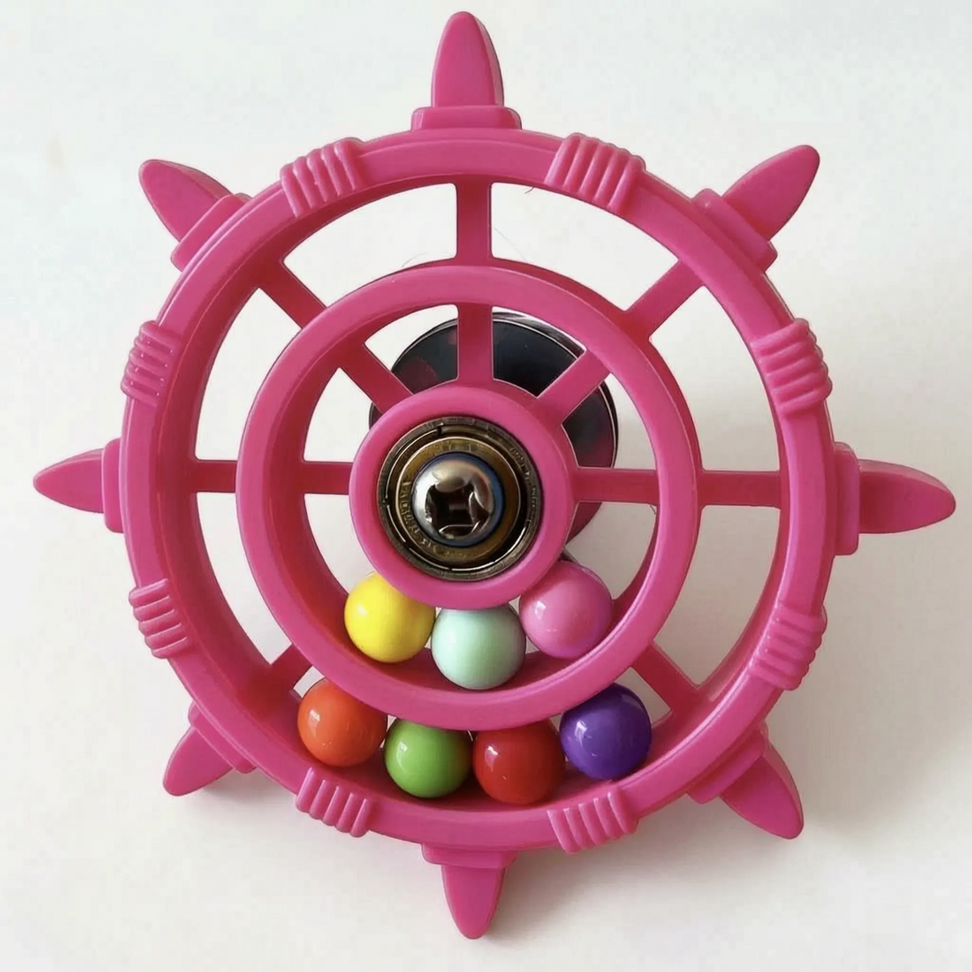 Pink wheel toy on a white surface, with a dark suction cup visible behind the spokes and a bearing at the center. 4