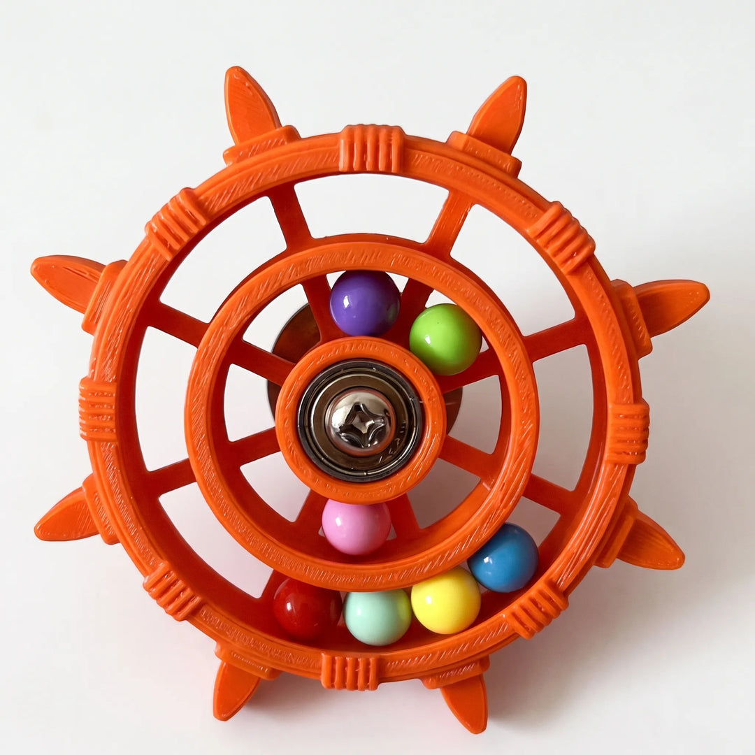 Orange version of the wheel toy with visible layered texture on the plastic, a metal screw center, and assorted colorful beads. 5