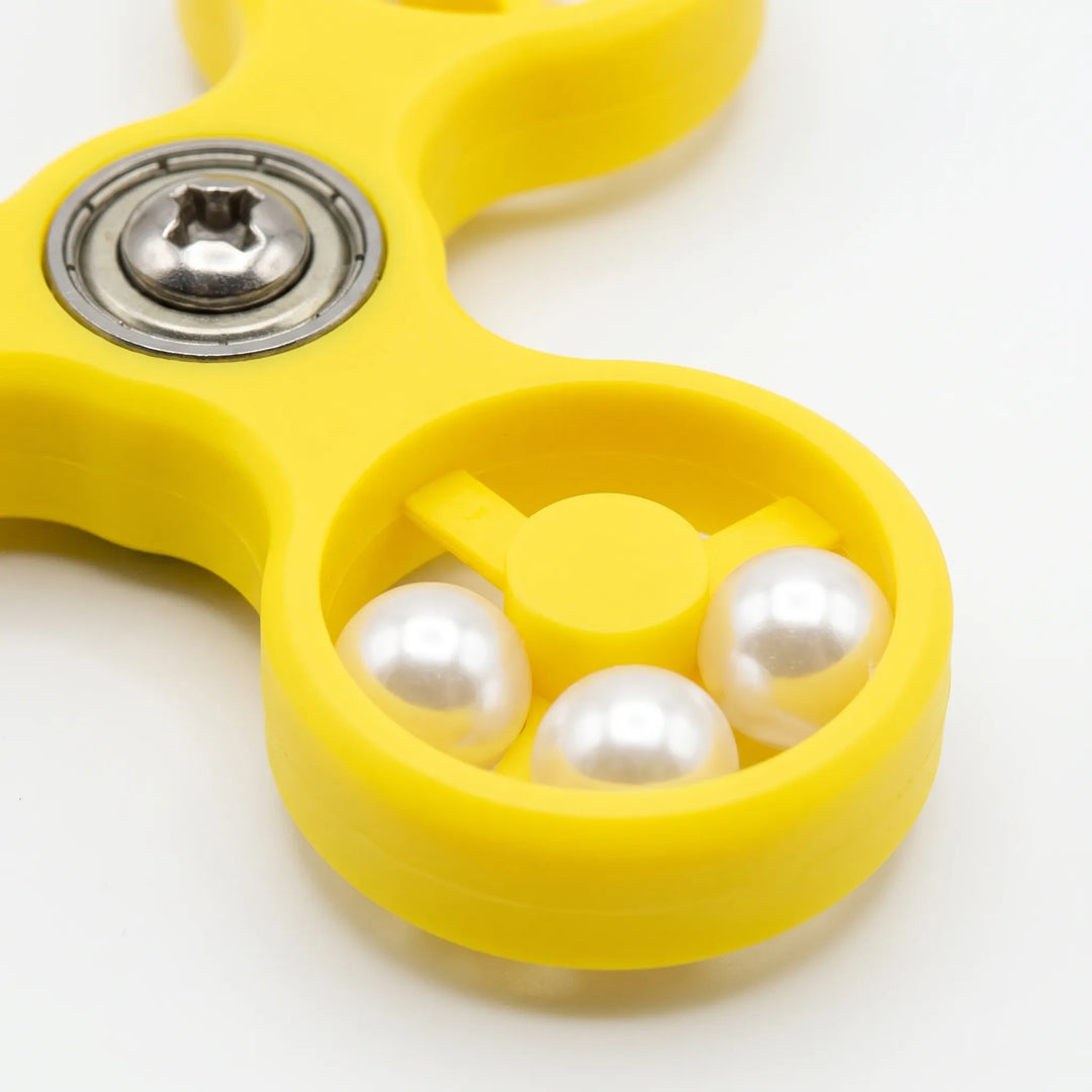 Close-up of one yellow spinner arm showing three white pearl beads inside the ring and the metal bearing and screw at the center. 4