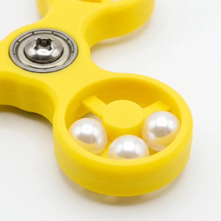 Close-up of one yellow spinner arm showing three white pearl beads inside the ring and the metal bearing and screw at the center. 4