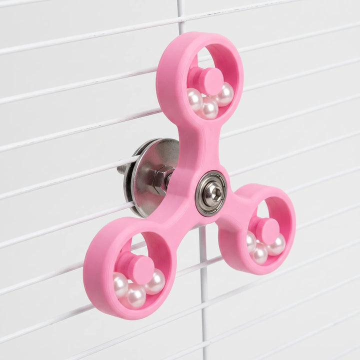 Pink version of the spinner angled to show the metal washer and bolt clamping it to white cage bars. 5