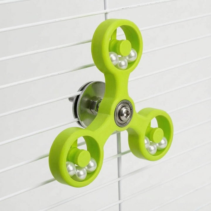 Lime green version of the spinner mounted on white cage bars, showing the steel washer and nut behind the center bearing. 6