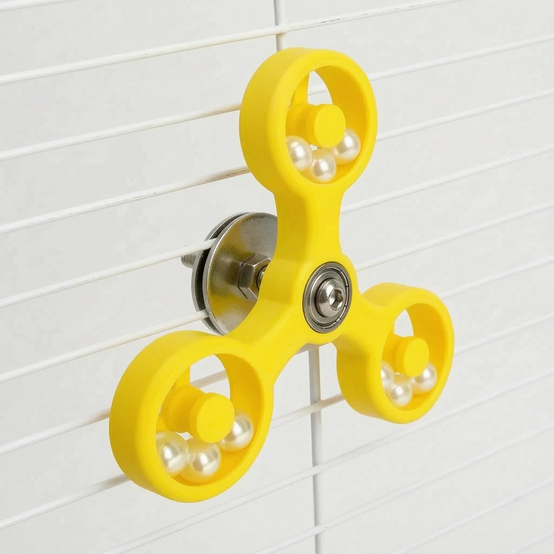 Angled view of the yellow spinner fastened to white cage wires with a metal washer and nut, pearl beads in each ring. 7