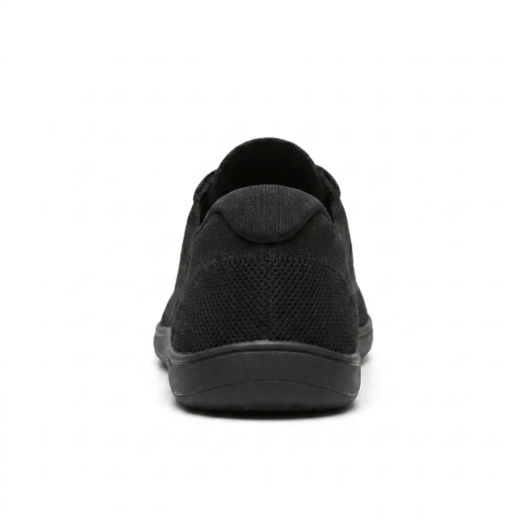 Rear view of a black knit sneaker showing the padded heel tab, mesh heel panel and flat sole.