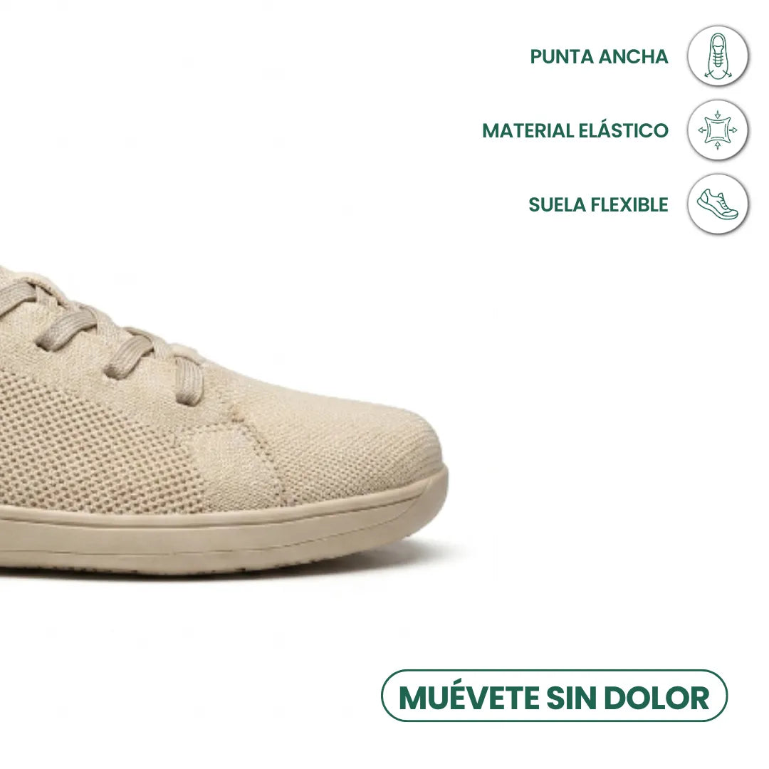 Close-up detail of the wide rounded toe of a beige sneaker with callouts for stretchy material and flexible sole.