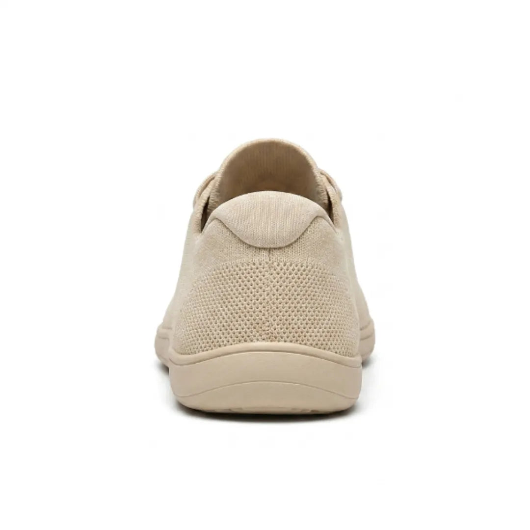 Rear view of a beige knit sneaker showing the padded heel tab, mesh heel panel and flat sole.