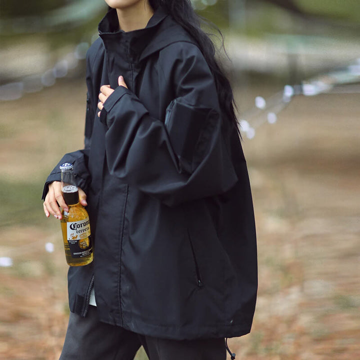 Black hooded jacket, side view with a zippered front pocket and drawcord hem.