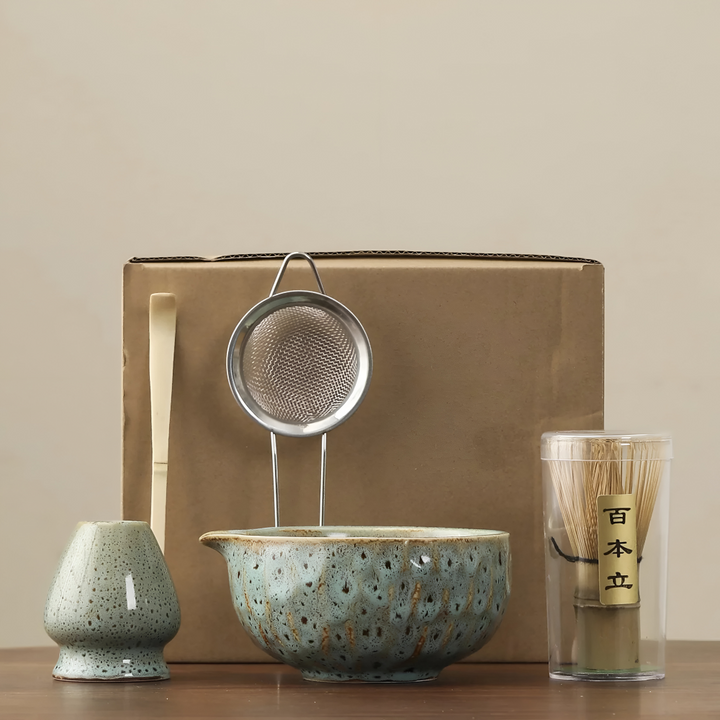 Another view of a pale blue-green speckled matcha set with bowl, whisk holder, mesh sifter, bamboo scoop and whisk in a tube.