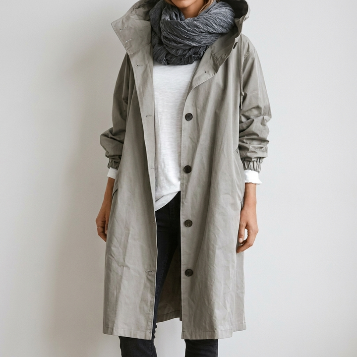 Women's Raincoat in light gray-green with hood and button front, worn open over a white tee and dark jeans.