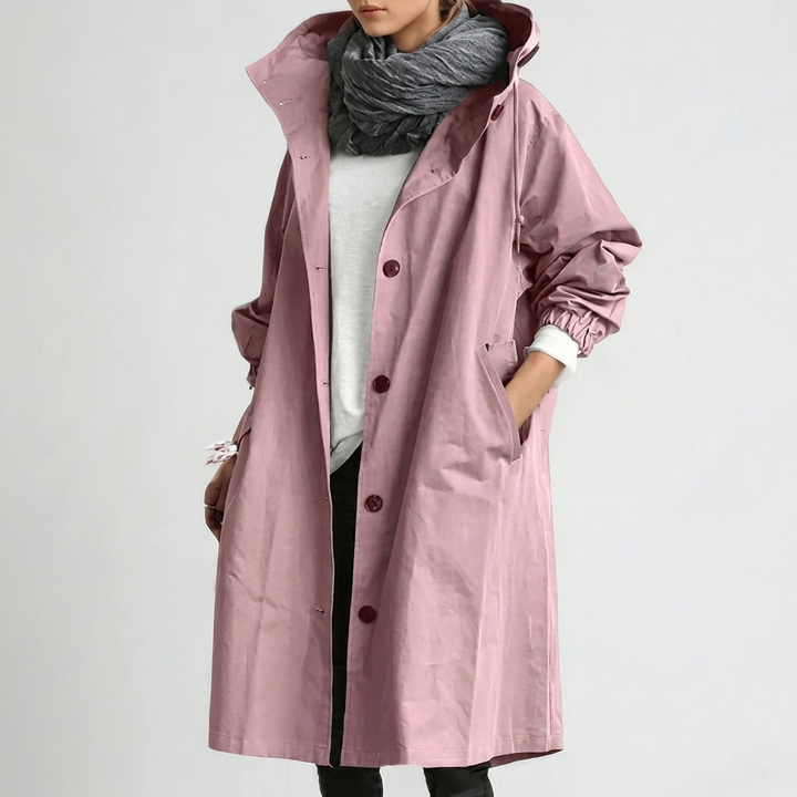 Women's Raincoat in dusty pink with hood and button front, shown on a model with one hand in a side pocket.