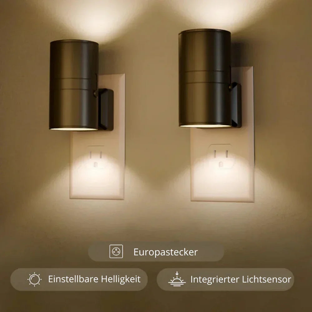 Another view of two black lamps in wall outlets casting light up and down.
