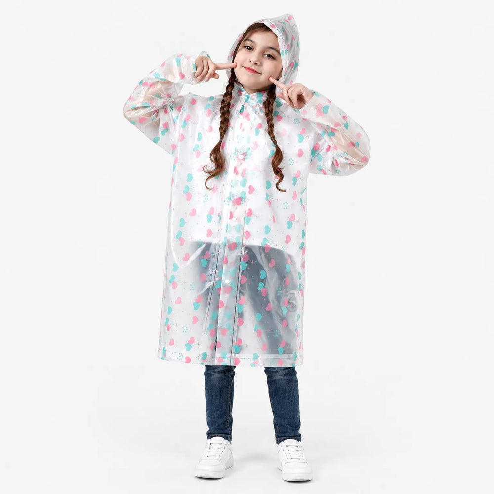 Smiling girl with braids poses in the hooded clear raincoat printed with pink and teal heart balloons, snaps closed. 2