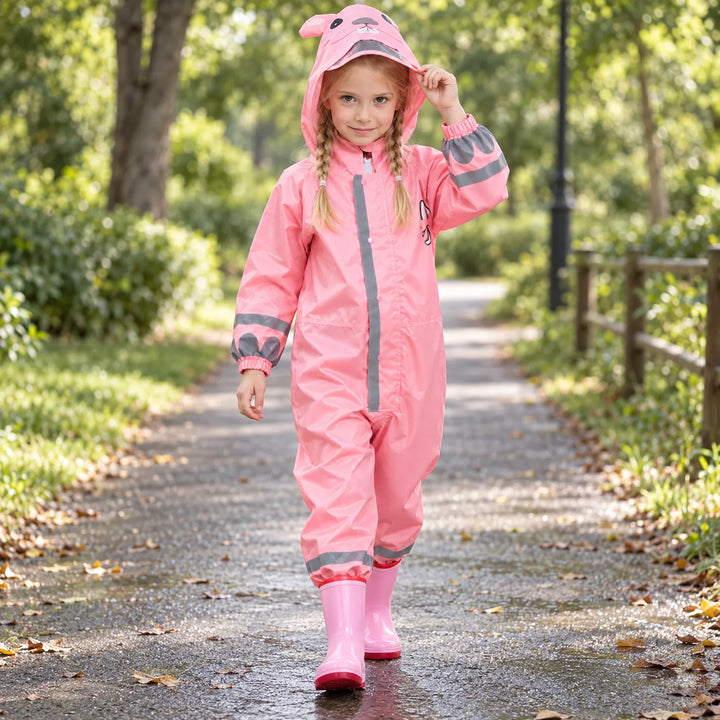 Girl with braids walking along a park path in the pink jumpsuit, hood up with animal ears and rain boots. 3