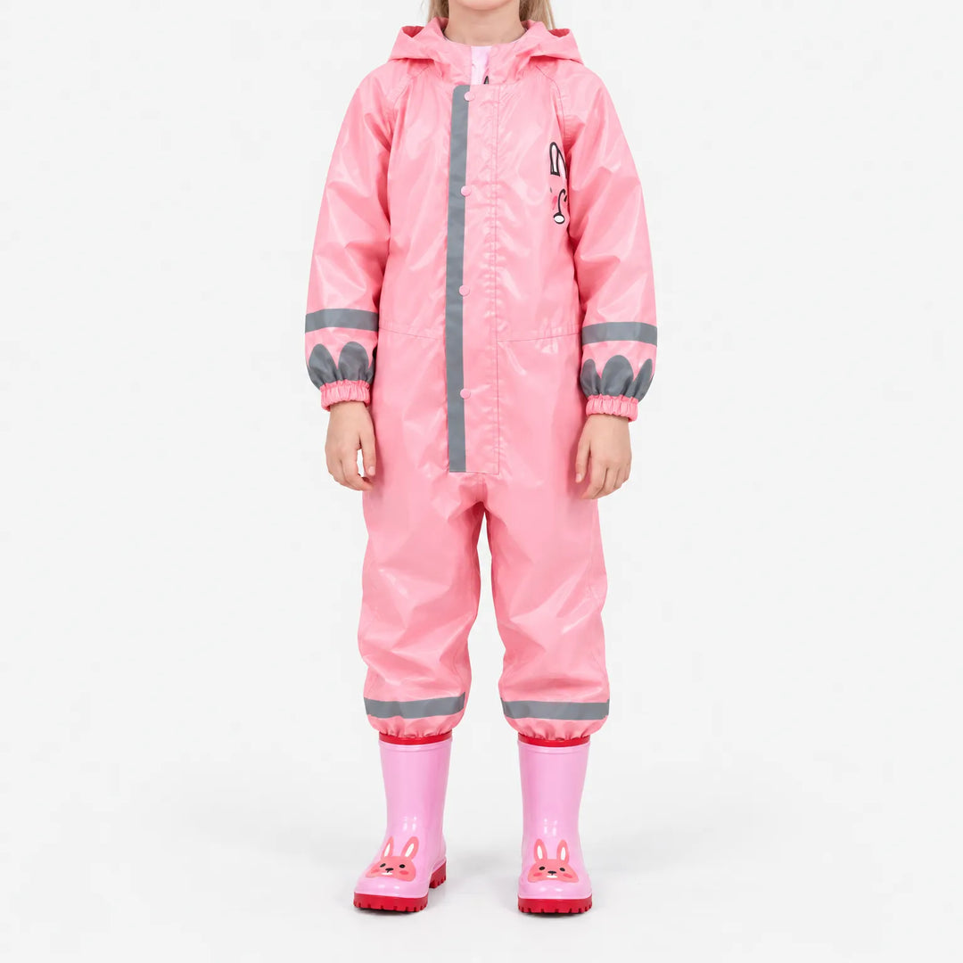Front view of the glossy pink jumpsuit on a child, with bunny chest print, reflective stripes and pink bunny rain boots. 9