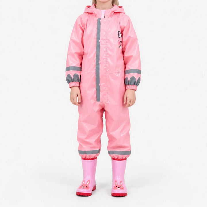 Front view of the glossy pink jumpsuit on a child, with bunny chest print, reflective stripes and pink bunny rain boots. 9