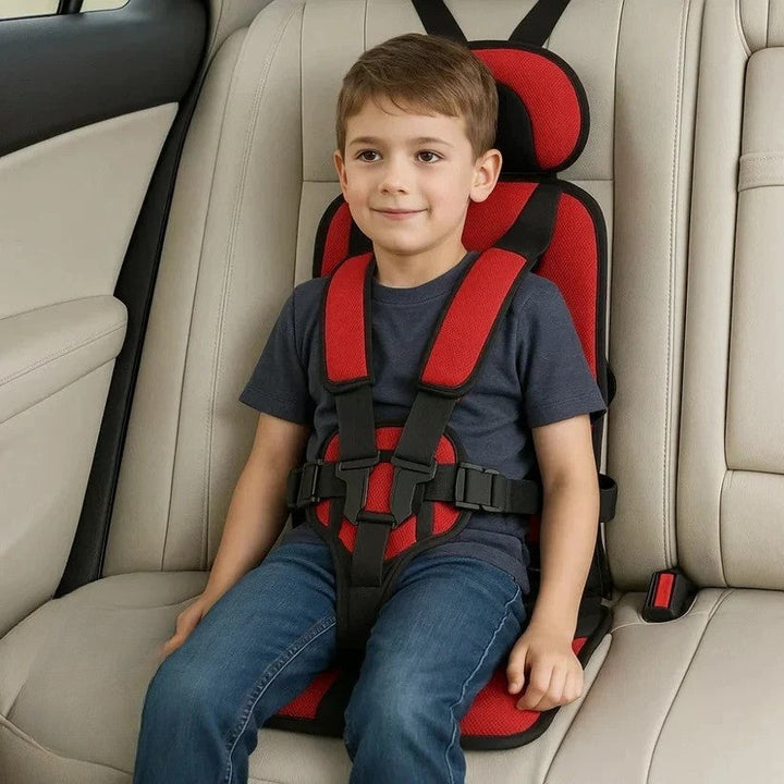 Red foldable kids travel seat with black five-point harness fastened.