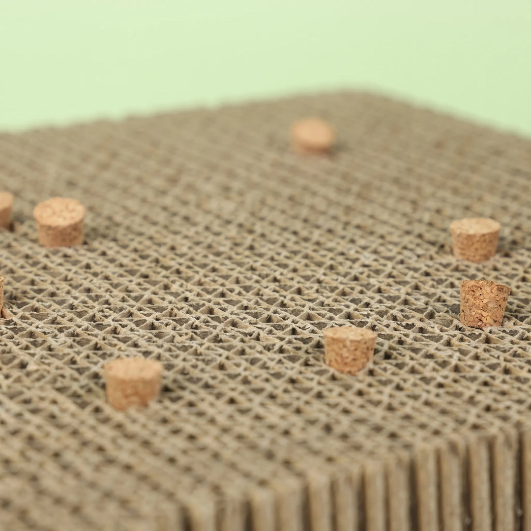Close-up of the honeycomb cardboard surface with small cork pieces embedded in it, against a pale green background. 4