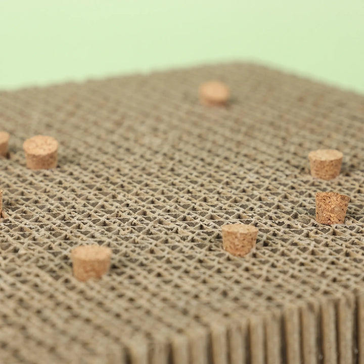 Close-up of the honeycomb cardboard surface with small cork pieces embedded in it, against a pale green background. 4