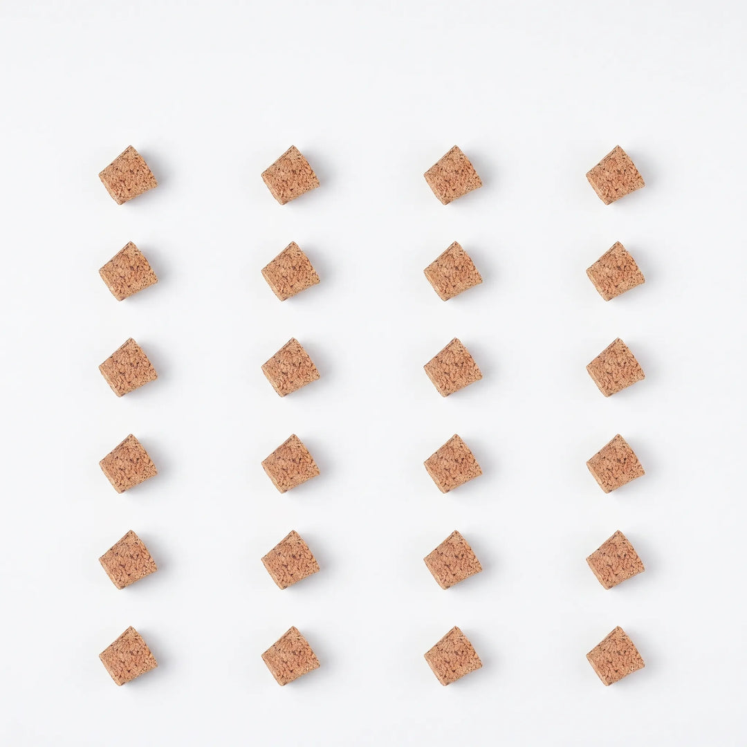 Flat lay of twenty-four loose tapered cork pieces arranged in a neat grid on a white background. 9