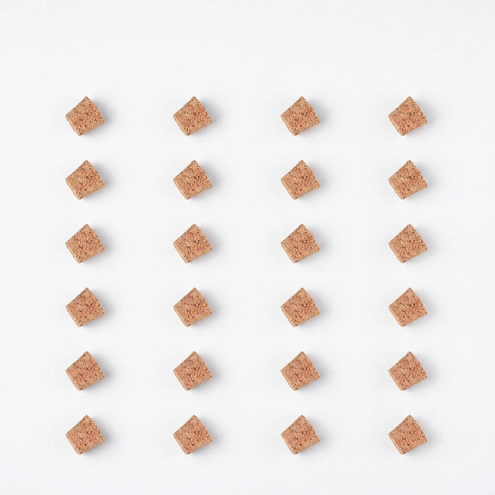Flat lay of twenty-four loose tapered cork pieces arranged in a neat grid on a white background. 9