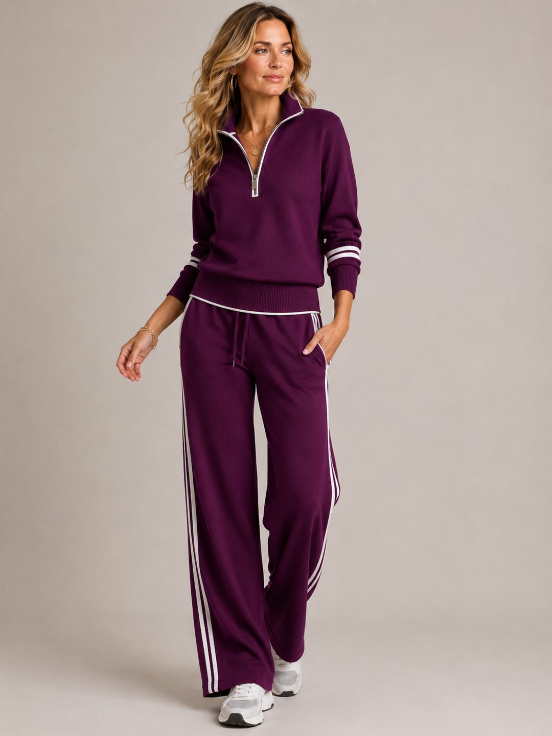 Woman walking in the deep plum set with white stripes on the sleeves and pant legs, with white sneakers. 2