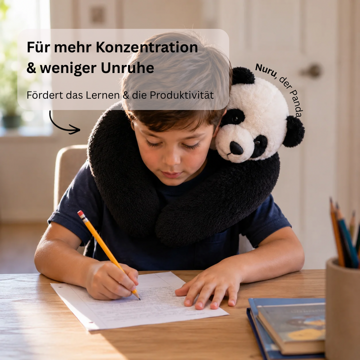 Boy writing at a wooden desk with the panda plush draped around his neck and shoulders like a collar. 9